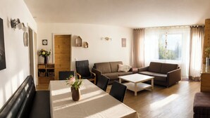 A living room with a dining table, sofas, and a wooden floor. - Majesta Leukerbad # 6-bed apartment, Dusche, WC by Interhome (Leukerbad)