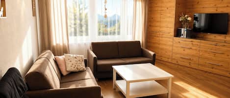 A modern living room with a sofa, a coffee table, and a TV on a wooden wall.