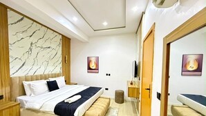 A modern bedroom with a bed, bedside tables, a mirror, and a wall-mounted TV. - Beautifully Styled 2 Bedroom Apartment in Salem Ikate. QQ (Ikate)