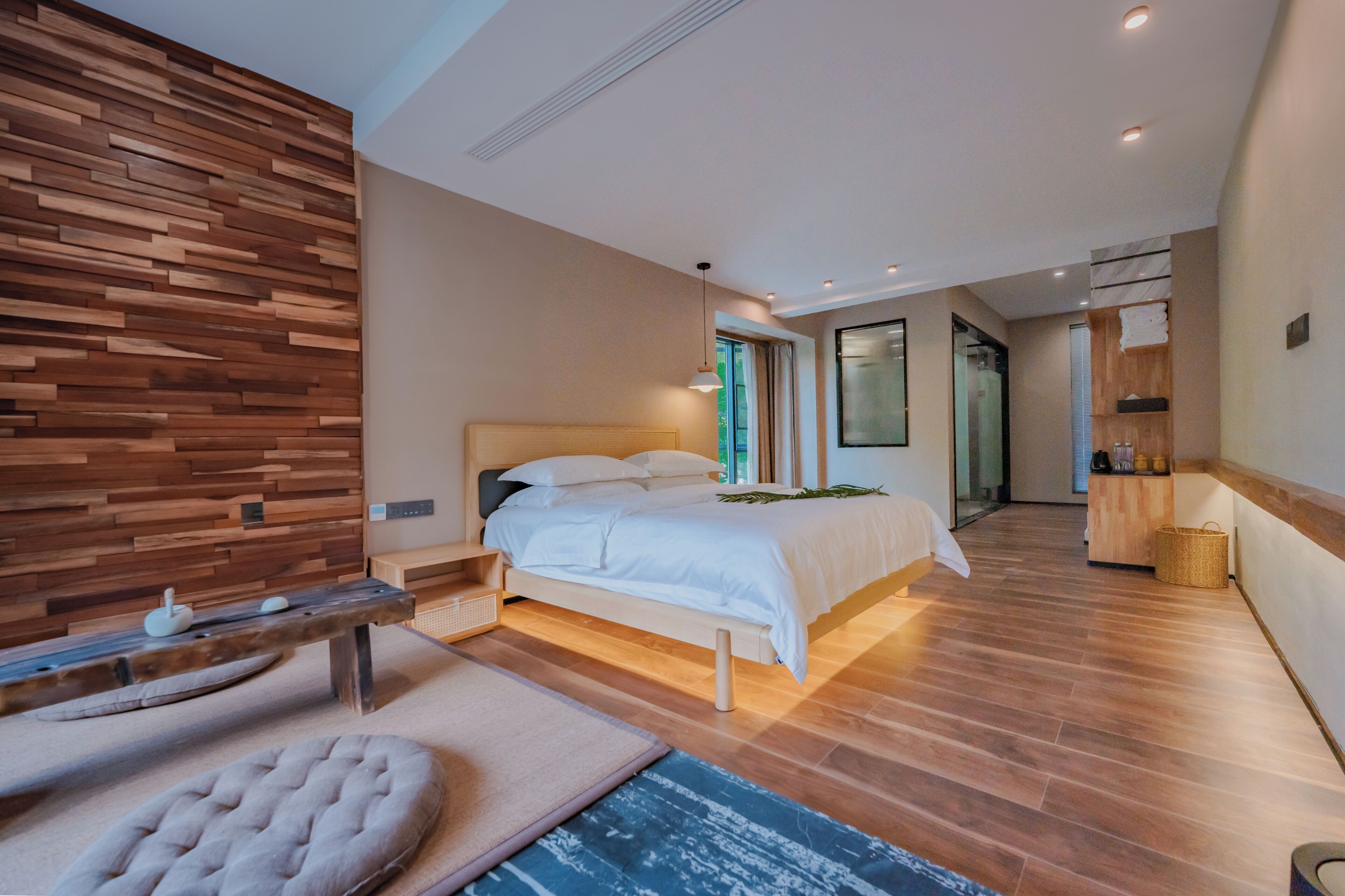 Un dormitorio moderno con cabecera de madera, cama con ropa blanca, mesita de noche y un banco.