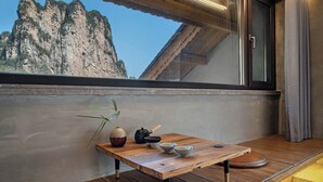 Uma mesa de madeira com tigelas e uma planta numa varanda com vista para as montanhas.