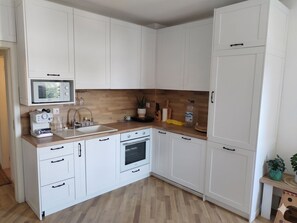 Eine moderne Küche mit weißen Schränken, einer Holz Arbeitsplatte, einem Einbauofen und einer Mikrowelle.