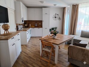 Eine moderne Küche mit weißen Schränken, einer Holzausziehtischplatte und einem Essbereich mit Tisch und Stühlen.