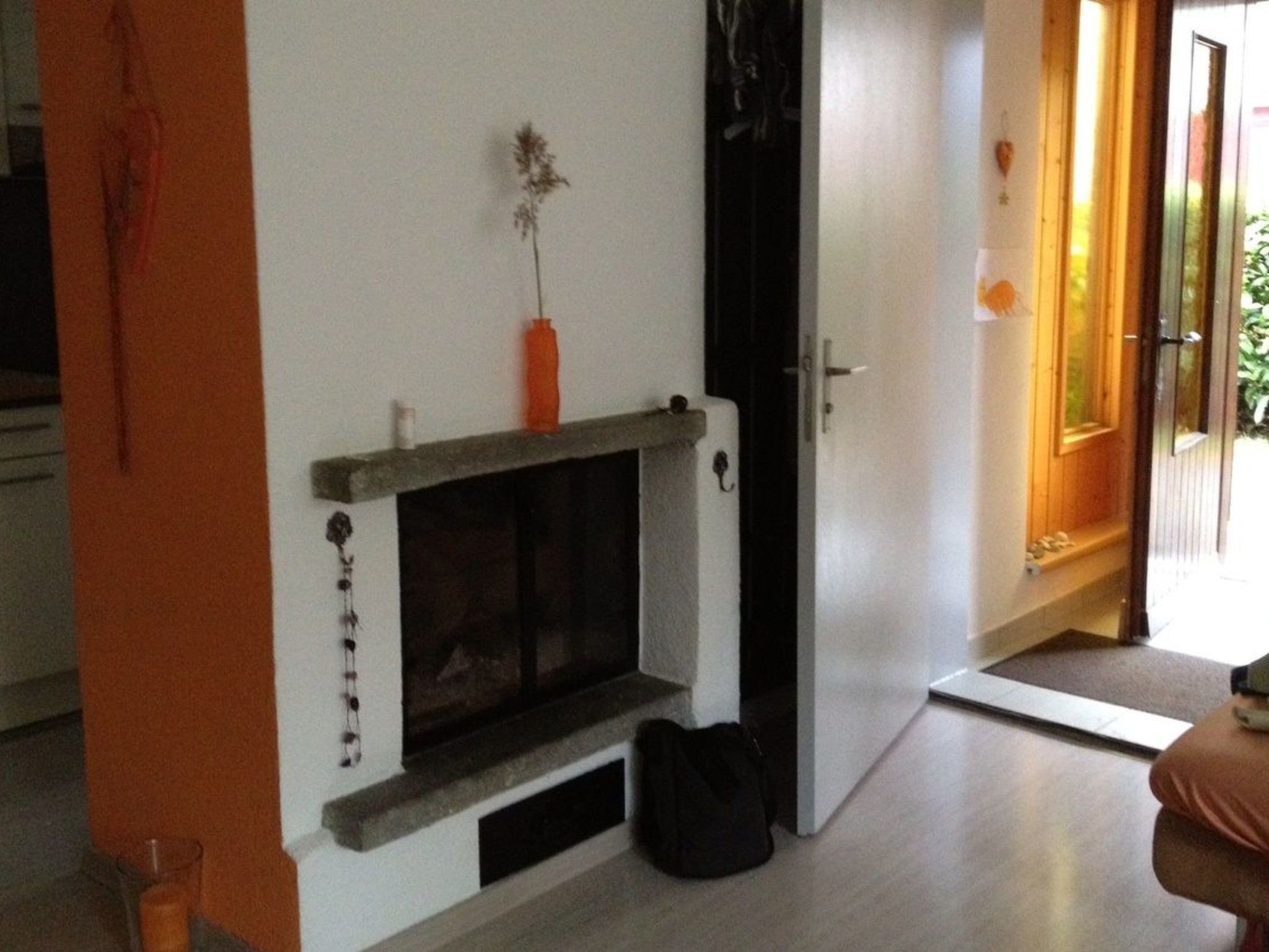 A room with a fireplace, a door leading to an outdoor area, and a bag on the floor.
