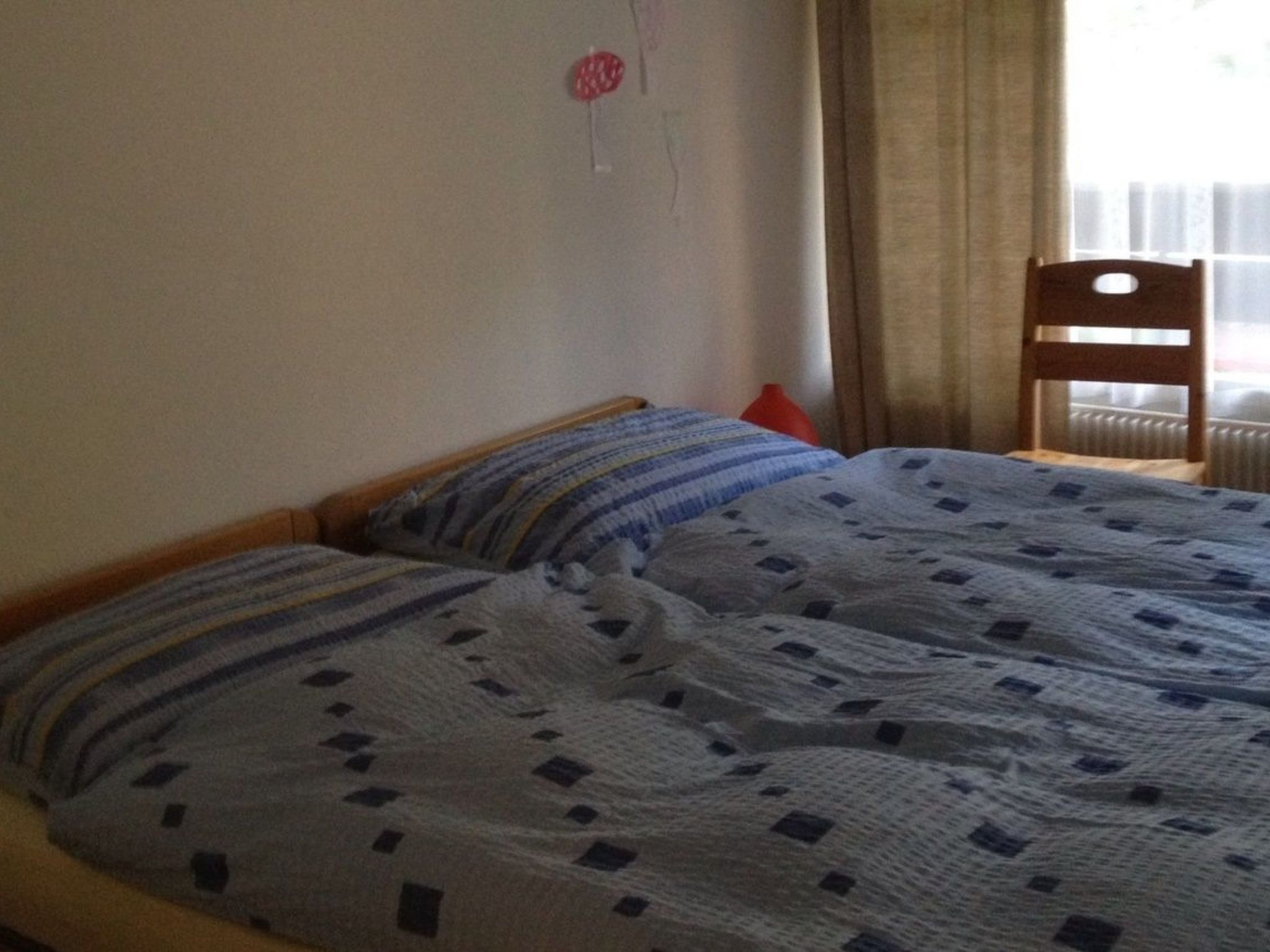 A bedroom with two beds, a wooden chair, and a radiator.