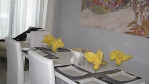 A dining area with a table set for four, white chairs, and a painting on the wall. - adfontes Ferien- & Wellnessappartements, (Bad Ragaz), by Interhome (Bad Ragaz)