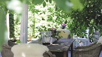 An outdoor seating area with wicker furniture, a glass table, and a candle holder.