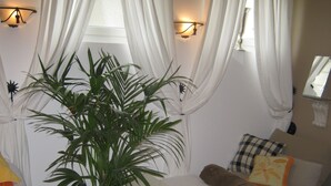 A room with a bed, a bench, a potted plant, and a window with curtains. - adfontes Ferien- & Wellnessappartements, (Bad Ragaz), by Interhome (Bad Ragaz)