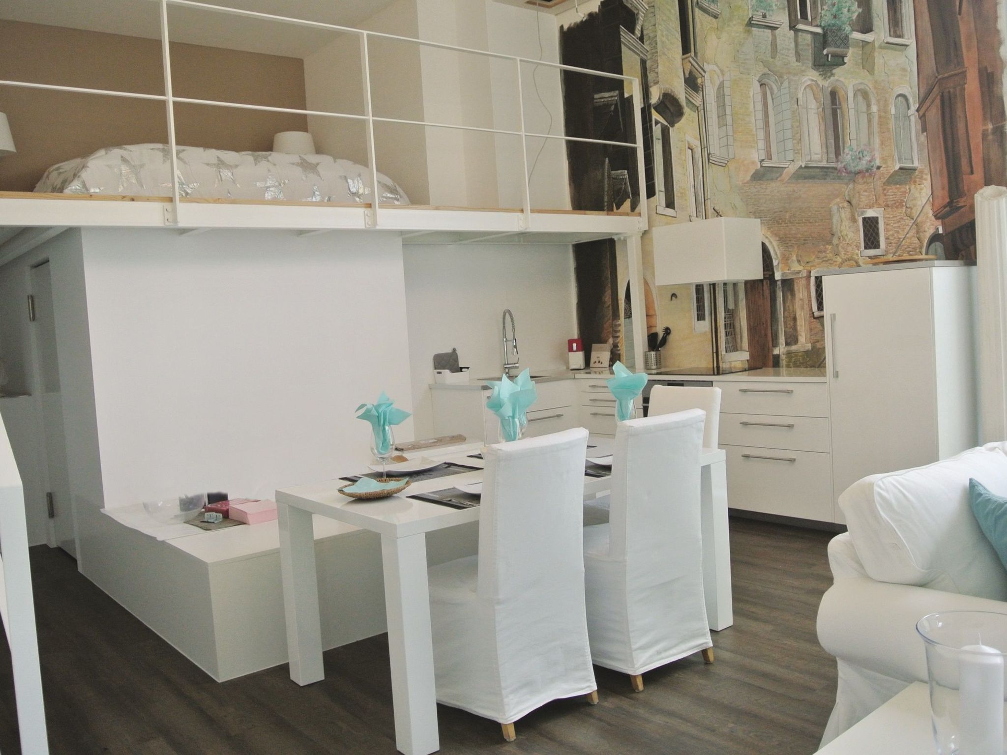A modern, compact living space with a kitchenette, a dining area, and a bedroom with a bunk bed.