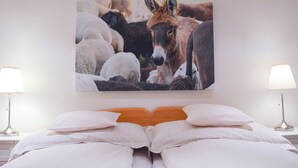 A bed with white bedding, a wall-mounted picture of a donkey, and two bedside lamps. - Rothmund, (Bad Ragaz), by Interhome (Bad Ragaz)