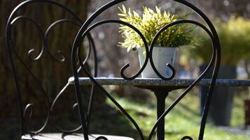 A metal chair with a heart-shaped backrest and a table with a potted plant.