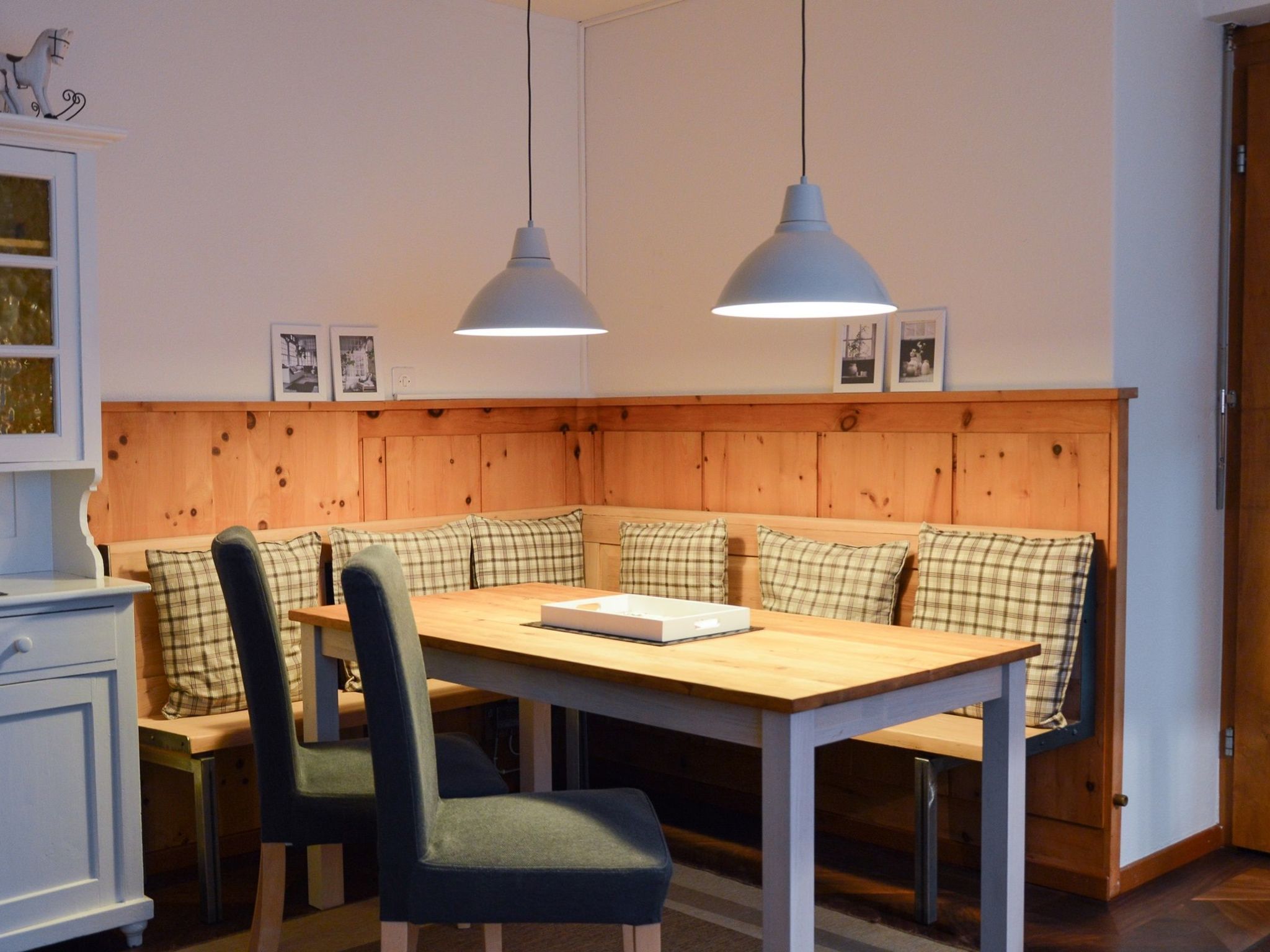 A dining area with a wooden bench seating, a table, and two pendant lights.