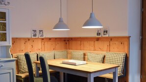 A dining area with a wooden table, bench seating, and two pendant lights. - Rothmund, (Bad Ragaz), by Interhome (Bad Ragaz)
