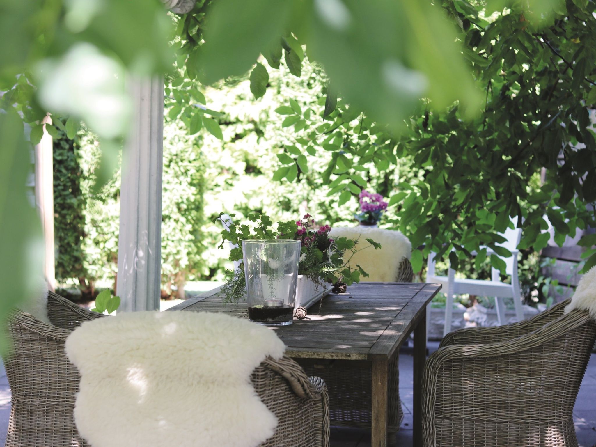 An outdoor seating area with wicker furniture, a glass table, and a candle holder.