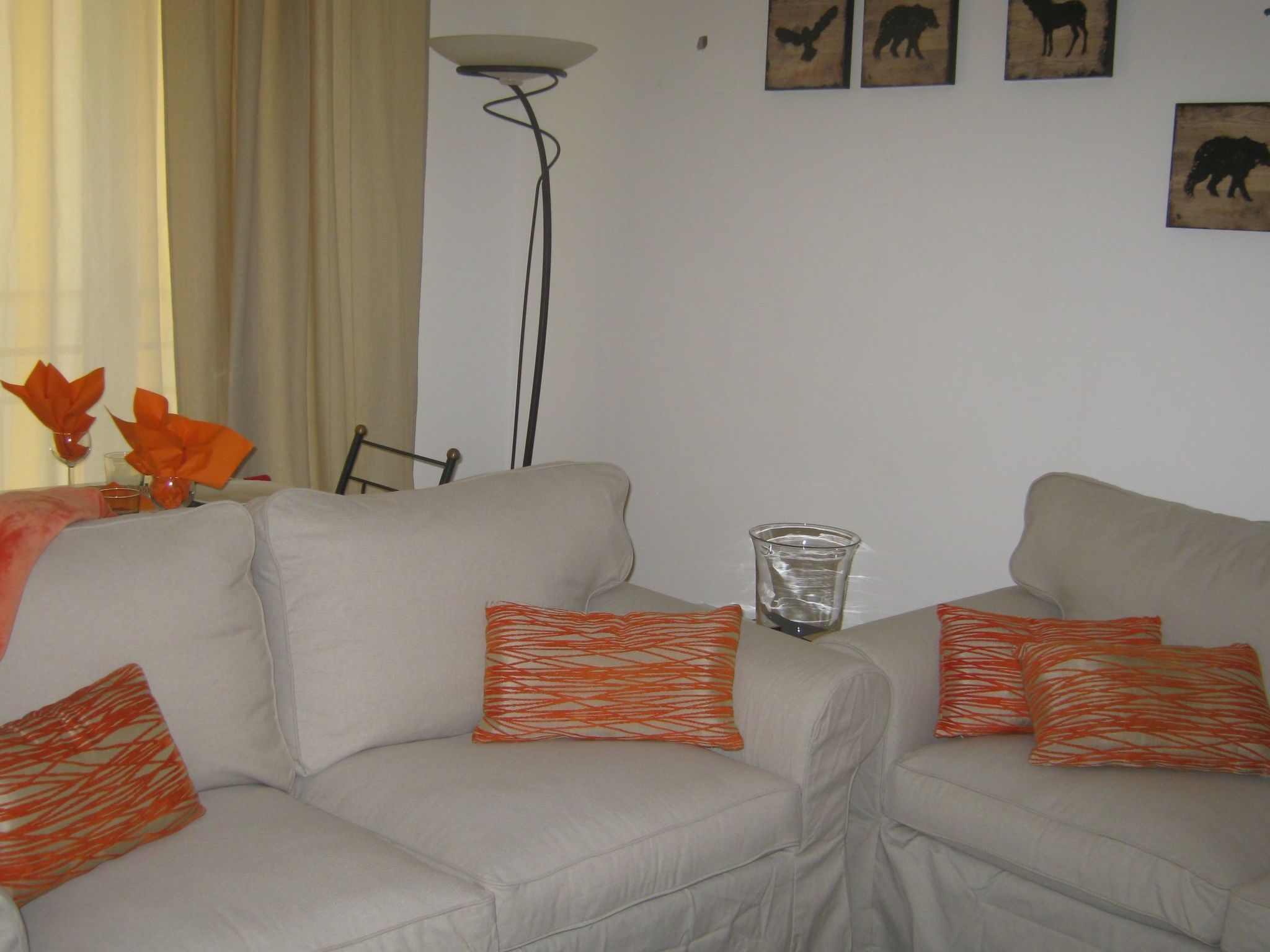 A living room with two sofas, orange patterned pillows, a floor lamp, and wall art.