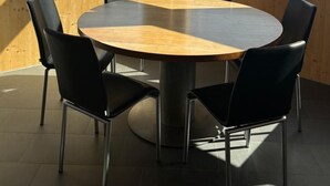 A round wooden table with black chairs, large windows with a mountain view, and pendant lights. - Casa Mia Pardiel, (Bad Ragaz), by Interhome (Bad Ragaz)