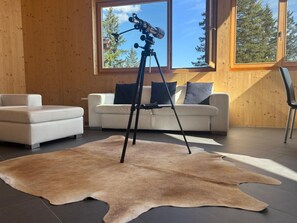 A room with a telescope on a tripod, a white sofa, and a large fur rug. - Casa Mia Pardiel, (Bad Ragaz), by Interhome (Bad Ragaz)