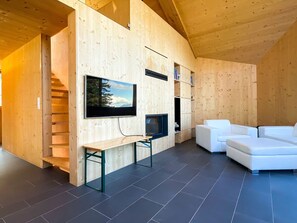 A modern interior with a wooden wall, a flat-screen TV, a sofa, and a small table. - Casa Mia Pardiel, (Bad Ragaz), by Interhome (Bad Ragaz)