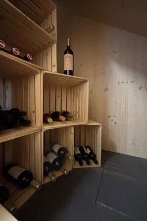 A wooden wine rack with bottles, a corkscrew, and a wine bottle. - Casa Mia Pardiel, (Bad Ragaz), by Interhome (Bad Ragaz)