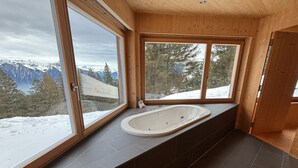 A modern bathroom with a freestanding bathtub, large windows offering mountain views, and dark tiled flooring. - Casa Mia Pardiel, (Bad Ragaz), by Interhome (Bad Ragaz)