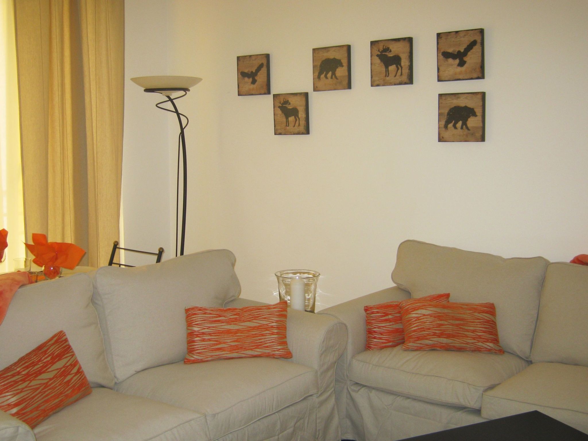 Una sala de estar con dos sofás, una lámpara de pie y arte mural que representa animales.