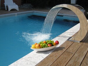 A pool with a waterfall feature and a bowl of fruit on the edge. - adfontes Ferien- & Wellnessappartements, (Bad Ragaz), by Interhome (Bad Ragaz)