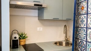 Una cocina con estufa integrada, un lavamanos y un refrigerador pequeño.