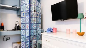 Una cocina moderna con salpicadero de azulejos, una cafetera, un cubo de basura, un televisor y una decoración minimalista.
