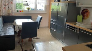 Una cocina moderna con refrigerador, microondas y comedor con mesa y sillas.