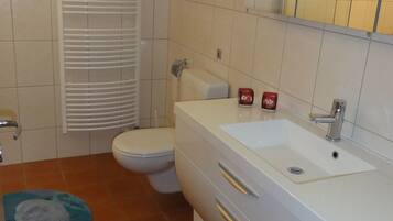 A bathroom with a toilet, sink, and a towel rack.