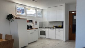 Eine Küche mit weißen Schränken, einem Esstisch mit Stühlen und einem Kühlschrank.