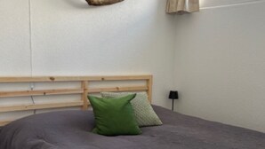 Ein Schlafzimmer mit einem Holzkopfende, einem Bett mit grauem Bettbezug und einem grünen Kissen.