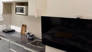 Eine moderne Küche mit integriertem Mikrowellenherd, einem flachbildfernseher an der Wand und einer Spüle aus Edelstahl.