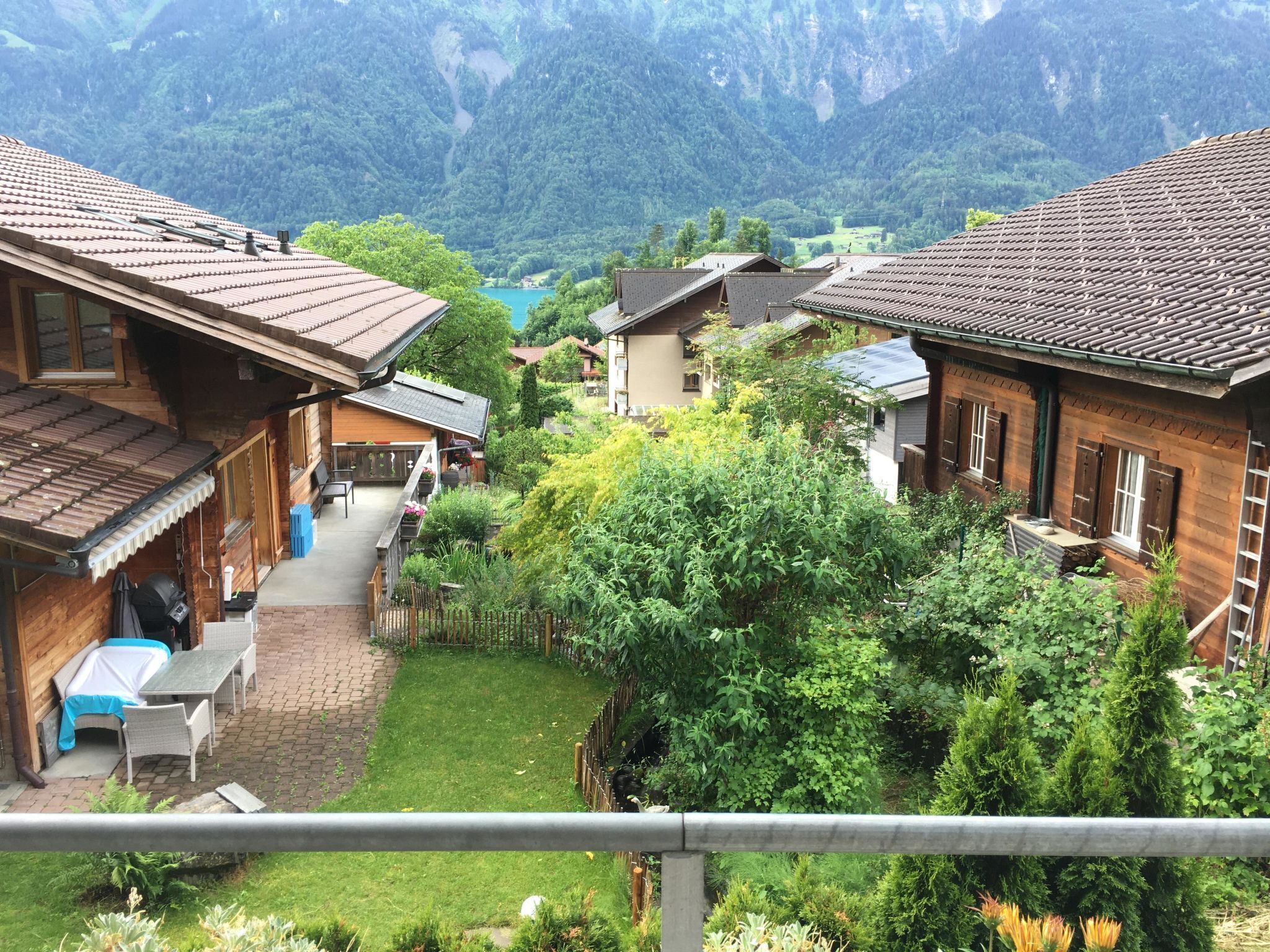 A traditional chalet with a wooden exterior, a covered patio with outdoor furniture, and a view of a mountainous landscape.
