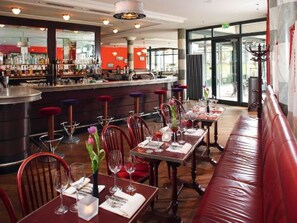 Un restaurant doté d’un bar, de plusieurs tables avec des chaises et d’un long banc le long du mur.