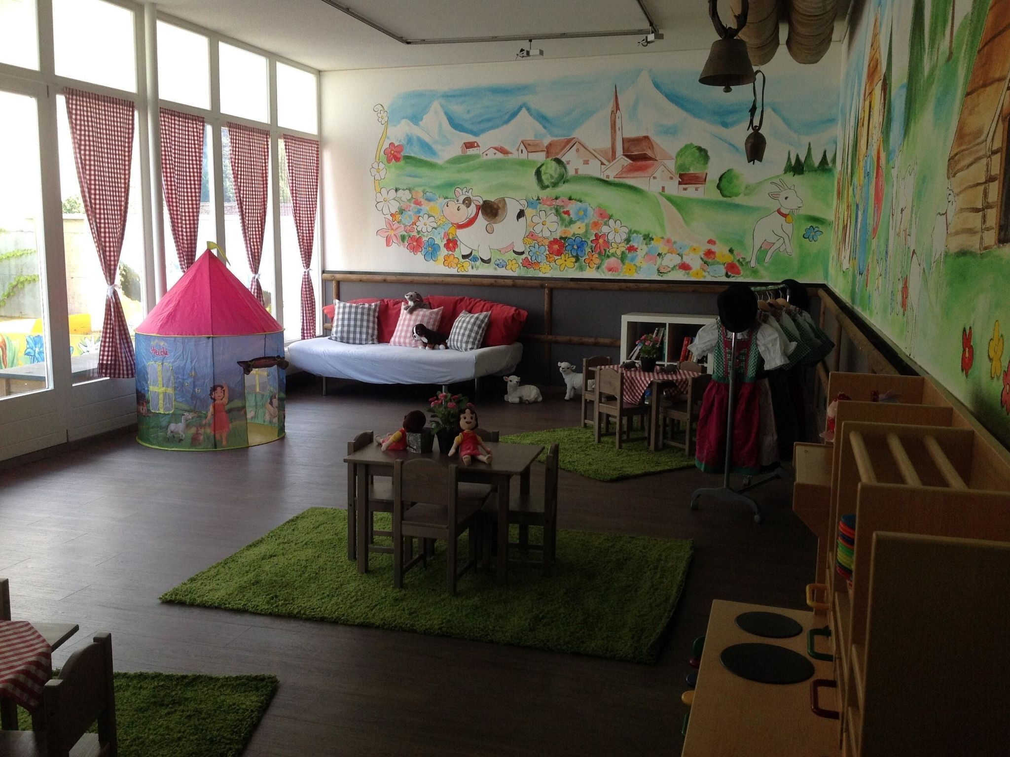 Une salle de jeux pour enfants, chaleureuse et accueillante, avec un lit, un parc pour bébé et une fresque murale.
