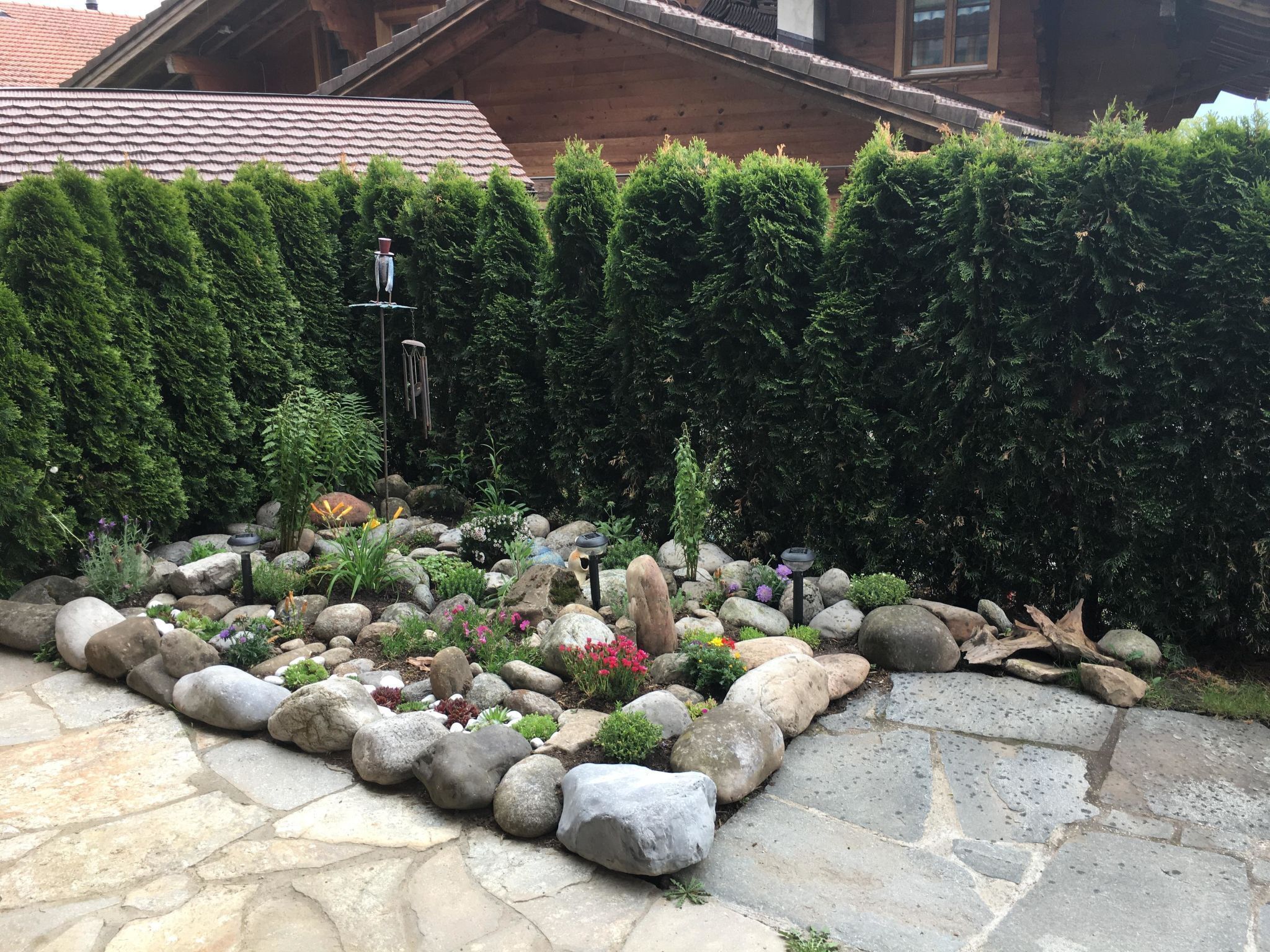 A garden with a stone pathway, rocks, and various plants.