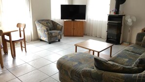 A living room with a sofa, armchair, TV, and a fireplace. - Schwizi's Holiday Apartments Appartement/Fewo, Dusche, WC, 2 Schlafräume No. 03 by Interhome (Ringgenberg)
