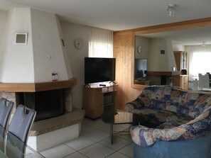 Un salon avec une cheminée, un téléviseur, un canapé et un coin repas.