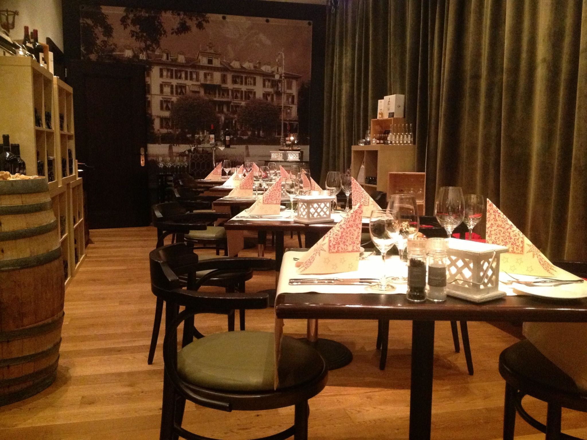A restaurant with tables set for dining, chairs, and a bar area with bottles.