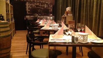 A restaurant with tables set for dining, chairs, and a bar area with bottles.