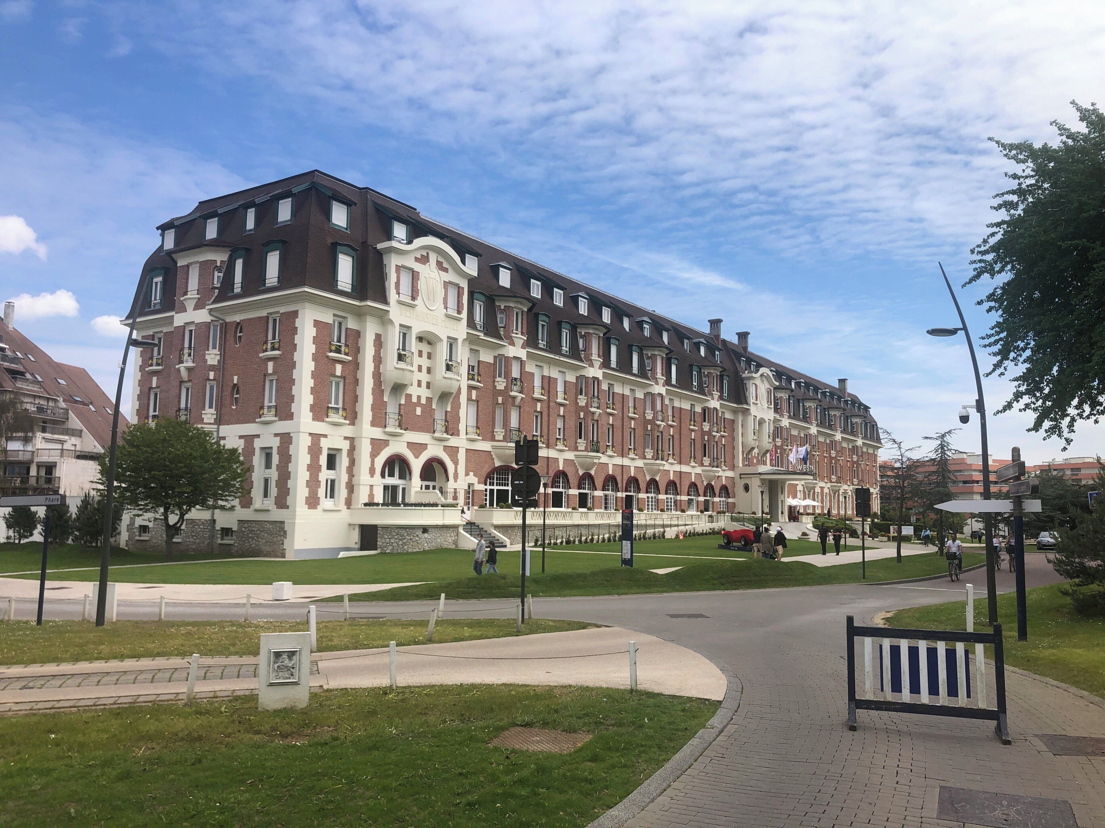 Een groot, meerhoog hotel met een klassieke architectuur, met een opvallende ingang en een verzorgd gazon.