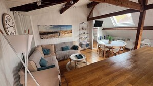 Un salon chaleureux avec un canapé, une table basse ronde et un coin repas comprenant des chaises et une table.