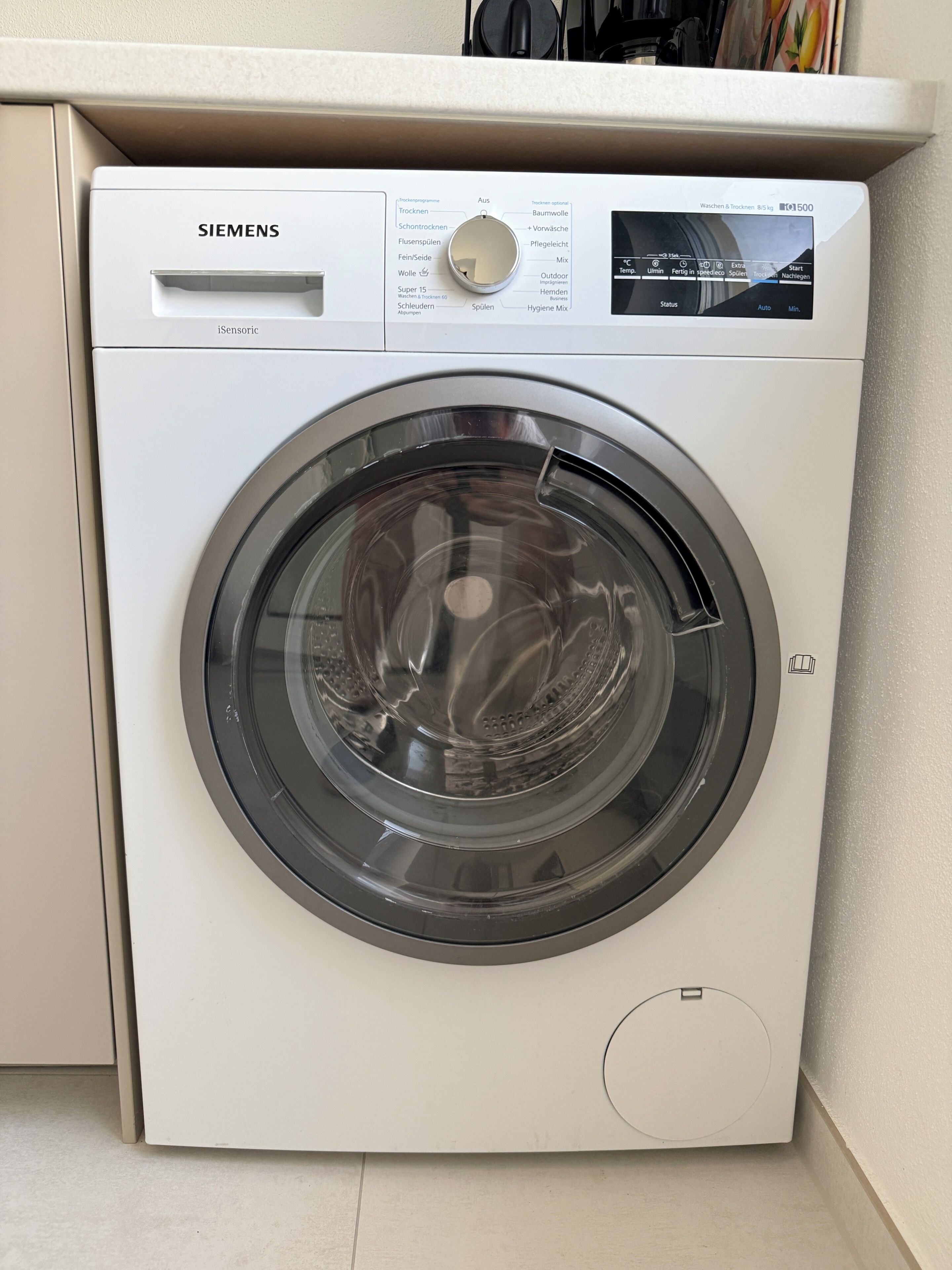 Un lave-linge Siemens doté d’un panneau de commande, situé dans une cuisine.