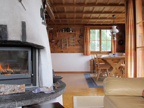 A cozy interior with a fireplace, wooden walls, a dining area, and a sofa. - Uf dr Braue Appartement/Fewo 6-Bettwohnung by Interhome (Beatenberg)