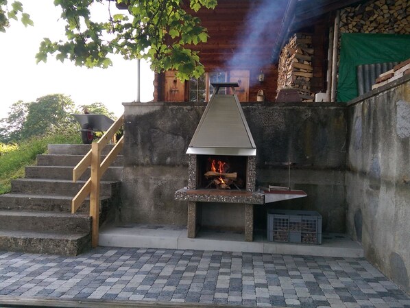 Una chimenea de piedra con chimenea, una escalera de madera y una carretilla.