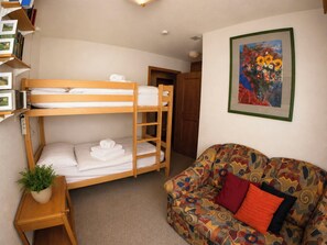 A room with a bunk bed, a sofa, a framed painting, and a small plant. - Residenz Darianne Leukerbad # 4-bed apartment, Dusche und Bad, WC by Interhome (Leukerbad)