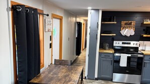 A modern kitchen with a wooden dining table, a built-in oven, and a refrigerator.