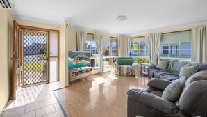 A spacious living room with a sofa, a television, and a view of the outdoors. - Yannarie: 3  BR, 1.5  BA House in South West Rocks, Sleeps 7 (South West Rocks)