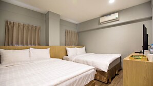 Ein Hotelzimmer mit zwei Betten, einem Schreibtisch, einer Klimaanlage und einem Fernseher.